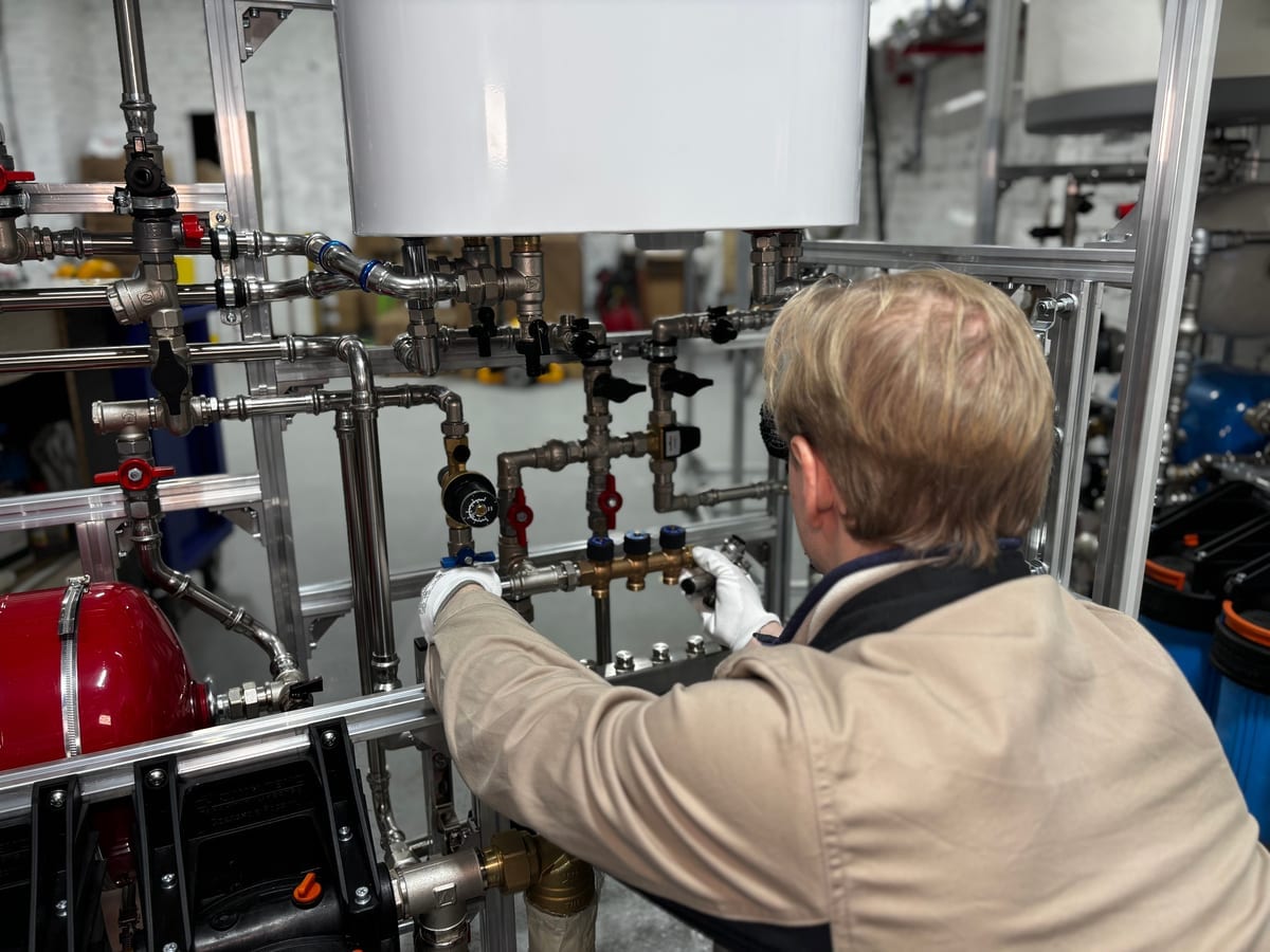 Anlagenmechaniker montiert die Verteilerbalken einer Heizungsanlage in einem Technikraum