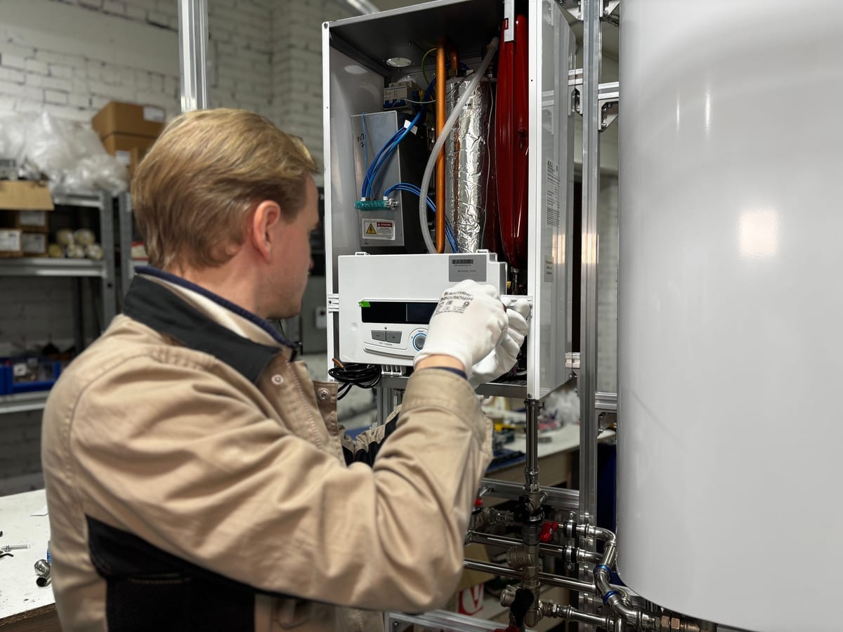 Anlagenmechaniker mit Handschuhen prüft die Regelung einer geöffneten Gastherme