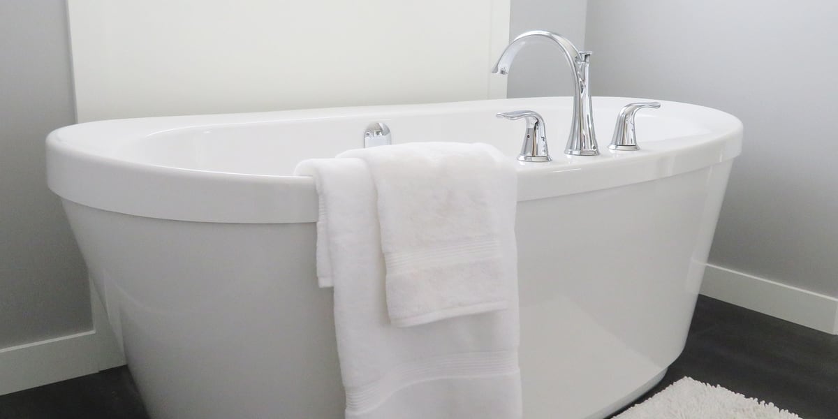 Vom Anlagenmechaniker angeschlossene freistehende Badewanne mit Armatur und Handtuch in einem sanierten Bad